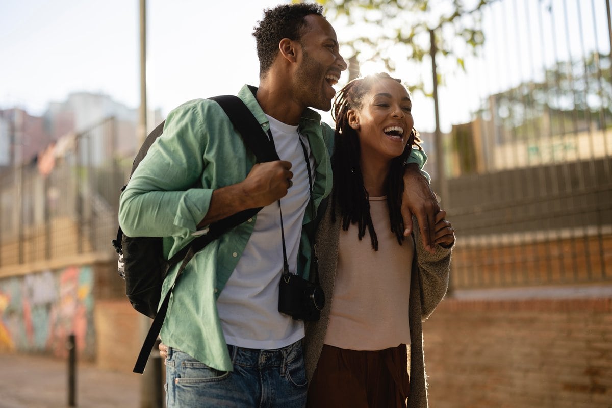 Embraced smiling African American couple with a camera visit the city